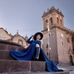 Sophisticated woman in a blue dress on Cusco street, capturing classic Peruvian architecture.